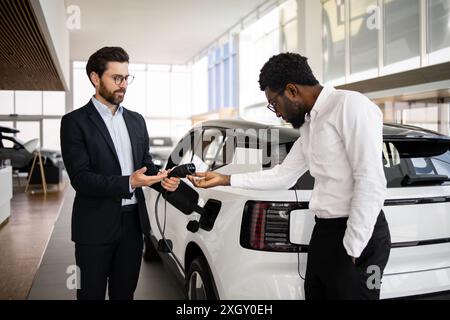 Concessionnaire vend SUV électrique à l'homme d'affaires dans la concession automobile Banque D'Images