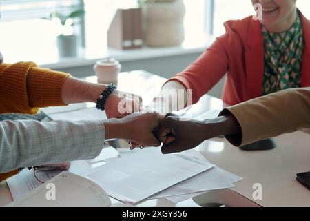 Gros plan des mains de membres de l'équipe multiethniques qui donnent un coup de poing pendant une réunion de bureau Banque D'Images