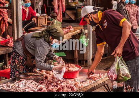 Un cambodgien qui achète de la viande tout en portant un masque facial pendant la pandémie de COVID-19. Marché de Kandal, Phnom Penh, Cambodge. © Kraig Lieb Banque D'Images