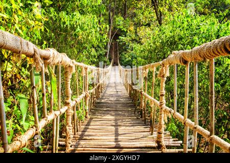 Pont suspendu simple et pittoresque au-dessus de la gorge. Passerelle étonnante faite de corde et de bambou. Beau pont suspendu parmi les bois verts. Banque D'Images
