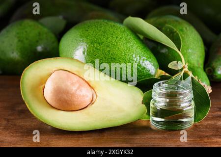 Avocats verts mûrs et huile d'avocat naturelle fraîche sur table en bois. Éco-produit sain de l'agriculture biologique. Soins de la peau, du corps et des cheveux. Cosmétique fait à la main Banque D'Images