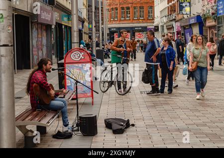 Belfast , County Antrim Irlande du Nord 05 juillet 2024 - busker assis sur un banc jouant de la guitare dans Ann Street Belfast City Centre Banque D'Images