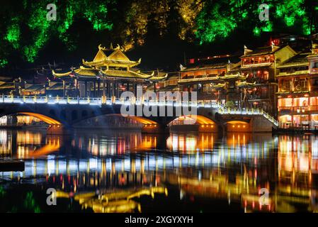 Belle vue nocturne de vieilles maisons traditionnelles chinoises en bois au bord de la rivière dans la ville antique de Phoenix (comté de Fenghuang), Chine. Banque D'Images