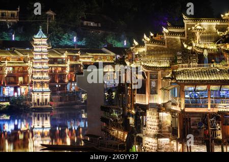 Belle vue nocturne de vieilles maisons traditionnelles chinoises en bois au bord de la rivière dans la ville antique de Phoenix (comté de Fenghuang), Chine. Banque D'Images