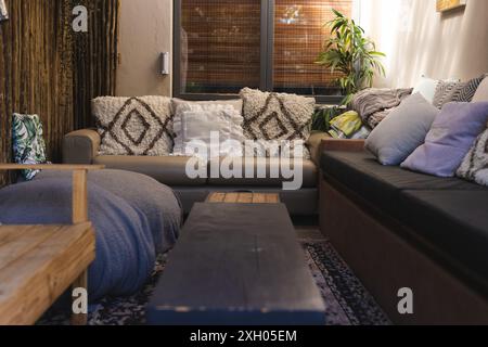 Salon confortable avec petite table, grand canapé avec coussins et fauteuil. Décoration intérieure et vie domestique. Banque D'Images