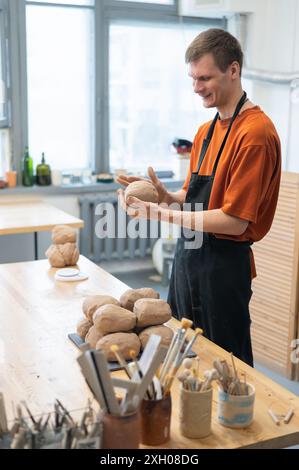 Potter pétrit l'argile avant de l'utiliser dans l'atelier. Photo verticale. Banque D'Images