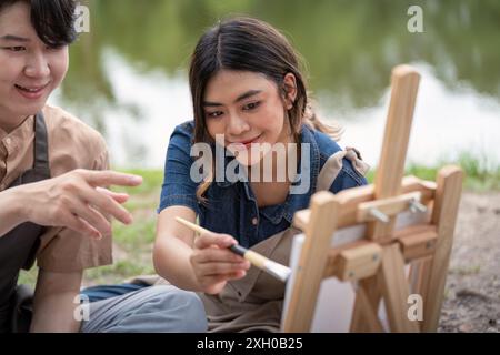 Couple pique-nique romantique dessinant à l'extérieur par le lac un jour ensoleillé. Moments artistiques et créatifs capturés dans la nature Banque D'Images