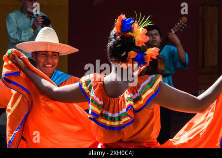 Grenade, Nicaragua - 24 mars 2019 : un danseur dans une robe orange vif célèbre avec une danse traditionnelle. Banque D'Images