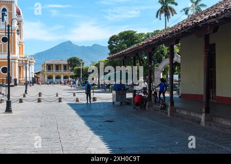 Grenade, Nicaragua - 24 mars 2019 : vie de rue animée avec le volcan Mombacho qui se profile au loin. Banque D'Images