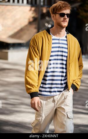 Un homme aux cheveux rouges dans une veste jaune élégante se promenant dans la rue de la ville. Banque D'Images