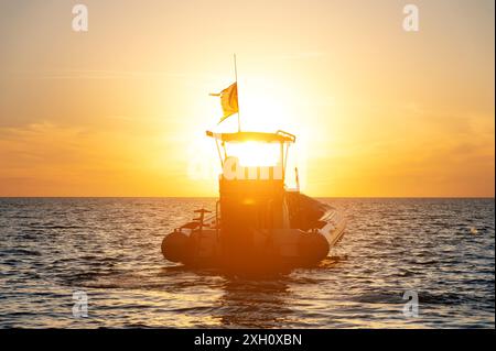 Petit catamaran de pêche au coucher du soleil. Transport en mer sans personnes dans la lumière du coucher du soleil. Crépuscule en mer Banque D'Images