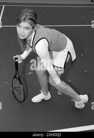 Joueur de tennis adolescent caucasien tenant une jambe avec un cheval charley et tenant une raquette de tennis et une balle de l'autre main. ÉTATS-UNIS Banque D'Images