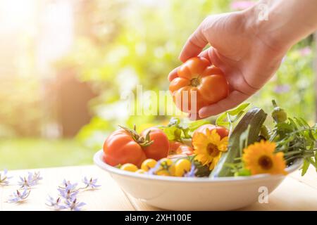 Légumes frais colorés dans un bol, élevés dans le propre jardin. Tomates, courgettes, fleurs et herbes Banque D'Images