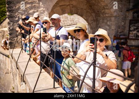 Mostar, Bosnie-Herzégovine. 11 juillet 2024. Les touristes regardent le musulman bosniaque Emel Tiro sauter du vieux pont de Mostar dans le cadre de la commémoration du 29e anniversaire du massacre de Srebrenica à Mostar, Bosnie-Herzégovine, le 11 juillet 2024. Photo : Denis Kapetanovic/PIXSELL crédit : Pixsell/Alamy Live News Banque D'Images
