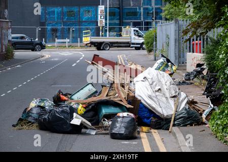 Site de basculement de mouches le 24 juin 2024 à Birmingham, Royaume-Uni. Le déversement illégal, également appelé déversement de mouches ou déversement de mouches, est le déversement illégal de déchets au lieu d'utiliser une méthode autorisée telle que la collecte en bordure de trottoir ou l'utilisation d'une décharge autorisée, et est considéré comme un comportement antisocial et un fléau pour de nombreuses communautés. Il s'agit du dépôt illégal de tout déchet sur terre, y compris les déchets déversés ou déversés sur un site sans autorisation d'accepter des déchets. Banque D'Images