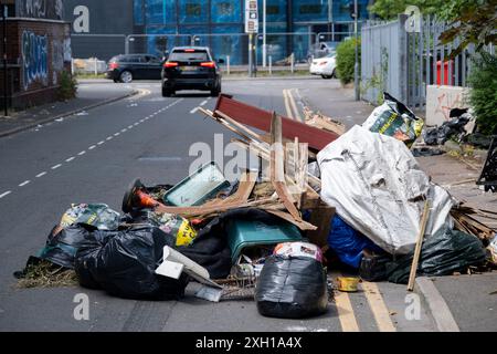 Site de basculement de mouches le 24 juin 2024 à Birmingham, Royaume-Uni. Le déversement illégal, également appelé déversement de mouches ou déversement de mouches, est le déversement illégal de déchets au lieu d'utiliser une méthode autorisée telle que la collecte en bordure de trottoir ou l'utilisation d'une décharge autorisée, et est considéré comme un comportement antisocial et un fléau pour de nombreuses communautés. Il s'agit du dépôt illégal de tout déchet sur terre, y compris les déchets déversés ou déversés sur un site sans autorisation d'accepter des déchets. Banque D'Images