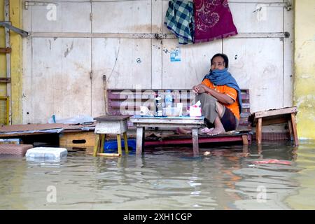 Gorontalo, Indonésie. 11 juillet 2024. Une femme repose sur un banc submergé par les eaux de crue causées par de fortes pluies à Gorontalo, Indonésie, le 11 juillet 2024. Crédit : Malik/Xinhua/Alamy Live News Banque D'Images