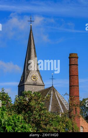 Tour d'église et cheminée derrière les plantes sous un ciel bleu avec quelques nuages, bredevoort, gueldre, pays-bas Banque D'Images