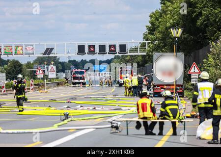 Unna, Allemagne. 11 juillet 2024. Les pompiers se trouvent sur l'autoroute A1 entre le carrefour Kamener Kreuz et Dortmund/Unna, près d'un camion de marchandises dangereuses (R) qui fuyait du gaz. La route a dû être fermée dans les deux sens en raison de la fuite du réservoir du camion. Crédit : Alex Talash/dpa - ATTENTION : le nom de l'entreprise et la plaque d'immatriculation du camion-citerne ont été pixelisés pour des raisons légales/dpa/Alamy Live News Banque D'Images