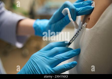 Dermatologue anesthésiant la zone cutanée touchée par le patient avant le retrait d'une nouvelle croissance Banque D'Images