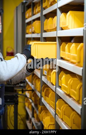 L'homme met une boîte jaune avec des pièces sur une étagère Banque D'Images