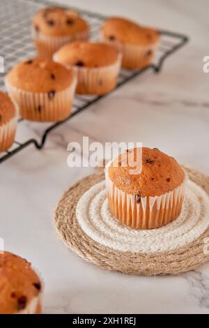 savoureux muffin à la vanille avec des pépites de chocolat, isolé avec plus de cupcakes sur grille noire sur marbre blanc Banque D'Images