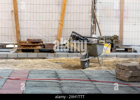 Une brouette bleue et du ciment dans le chantier de construction. Banque D'Images