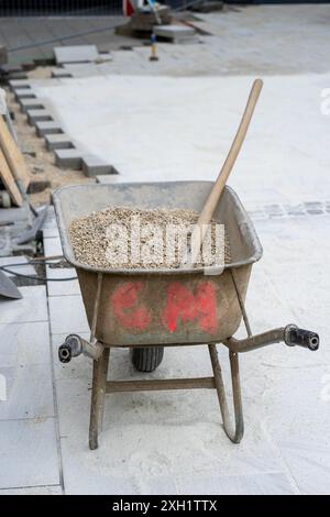 Une brouette bleue et du ciment dans le chantier de construction. Banque D'Images