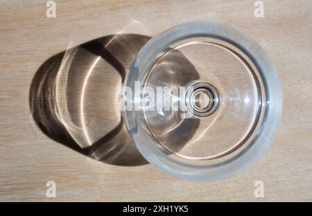 Vin ou verre à grenaille vu de dessus, éclairé par le soleil, avec ombre sur fond de bois Banque D'Images