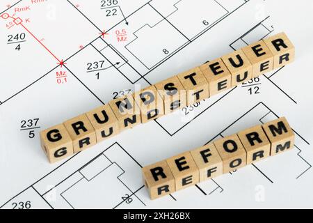 Image de symbole de la réforme de l'impôt foncier : les cubes de lettres sur un plan de développement montrent le mot allemand GRUNDSTEUERREFORM (réforme de l'impôt foncier) Banque D'Images