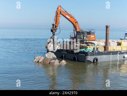 Travaux de protection contre l'érosion côtière avec des machines provenant d'une barge en mer, Cromer, Norfolk, Angleterre, Royaume-Uni, Europe Banque D'Images