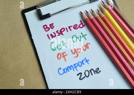 Concept de Be Inspired sortez de votre zone de confort écrivez sur papier isolé sur fond de bois. Banque D'Images