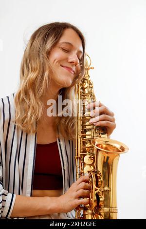 Fille blonde décontractée embrassant son saxophone Banque D'Images