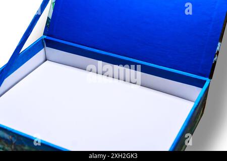 Une petite boîte ouverte avec un intérieur blanc et une couverture en tissu bleu sur fond blanc. Banque D'Images