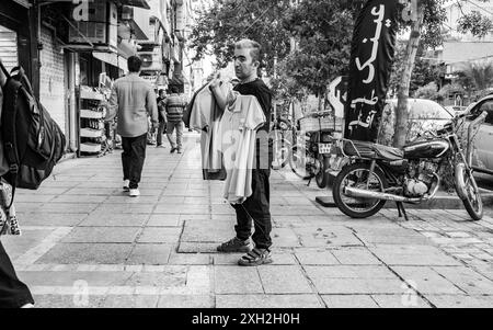 Homme vendant des T-shirts sur le trottoir. Banque D'Images