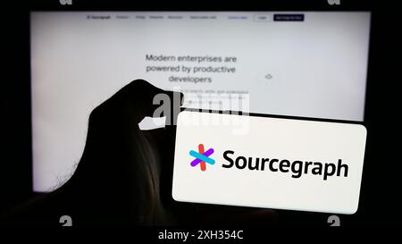 Personne tenant le téléphone portable avec le logo de la société américaine de renseignement de code Sourcegraph Inc en face de la page Web. Concentrez-vous sur l'affichage du téléphone. Banque D'Images