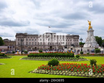 Londres, Angleterre - 04 juin 2024 : Palais de Buckingham avec statue de Victoria et arrangements floraux. Touristes visibles dans la rue Banque D'Images