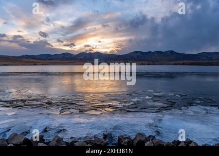 Lac Winter Mountain - vue rapprochée de fragments minces de glace brisée qui s'accumulent sur la rive du lac Bear Creek par une soirée de décembre orageuse. Lakewood, Colorado, États-Unis. Banque D'Images