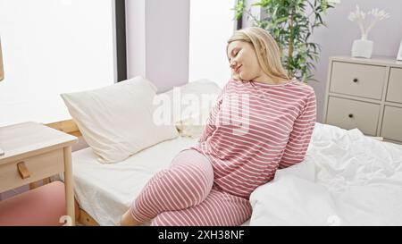 Une jeune et belle femme blonde caucasienne se détend à la maison dans sa chambre. Banque D'Images