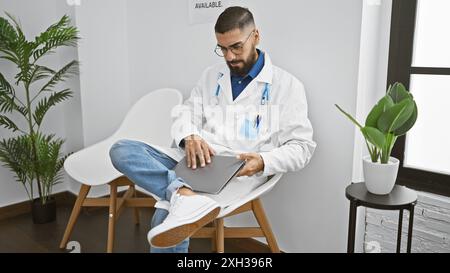 Médecin barbu utilisant la tablette à l'intérieur de la clinique moderne, homme portant un manteau blanc, professionnel de la santé dans la salle blanche intérieure. Banque D'Images