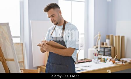 Un jeune homme hispanique à la barbe dessine dans un studio d'art, incarnant des thèmes créatifs et académiques. Banque D'Images