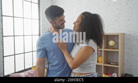 Un couple aimant se tient étroitement ensemble dans un salon confortable et bien éclairé, incarnant une relation harmonieuse. Banque D'Images