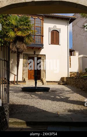 Astorga, Espagne - 4 juin 2023 : un aperçu d'une cour paisible à Astorga, Espagne. Une fontaine se trouve au centre du chemin de gravier, et un b blanc Banque D'Images