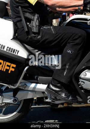 Un officier du département du shérif du comté de Henderson sur une moto patrouille dans la rue avant le début d'une parade du 4 juillet en Caroline du Nord. Banque D'Images