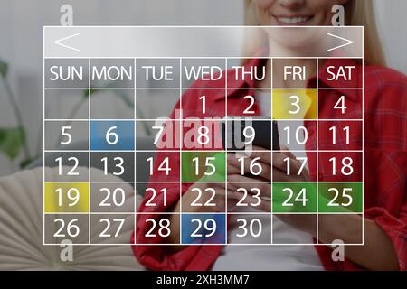 Femme faisant l'horaire dans le téléphone portable. Calendrier virtuel avec dates marquées au premier plan Banque D'Images