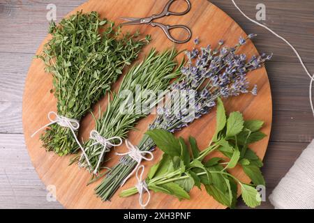 Différentes herbes aromatiques et ciseaux sur table en bois, vue de dessus Banque D'Images