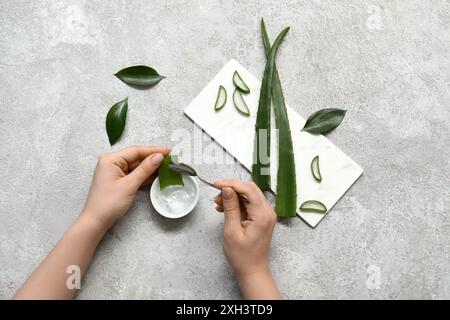 Femme faisant du gel d'aloe vera sur fond gris Banque D'Images