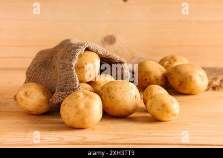 Sac avec pommes de terre crues sur fond en bois Banque D'Images