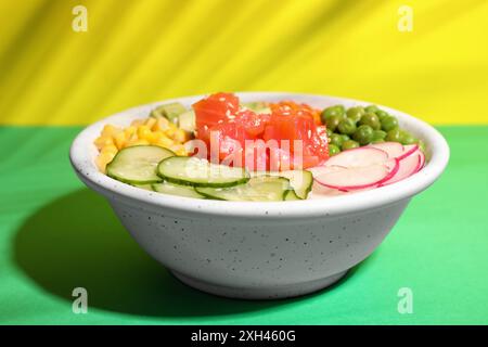 Salade délicieuse avec du saumon et des légumes dans un bol sur fond de couleur Banque D'Images