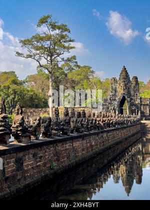 Le pont vers Angkor Thom, bordé des deux côtés de figurines se terminant par une entrée en arc encorbée, Cambodge. Banque D'Images